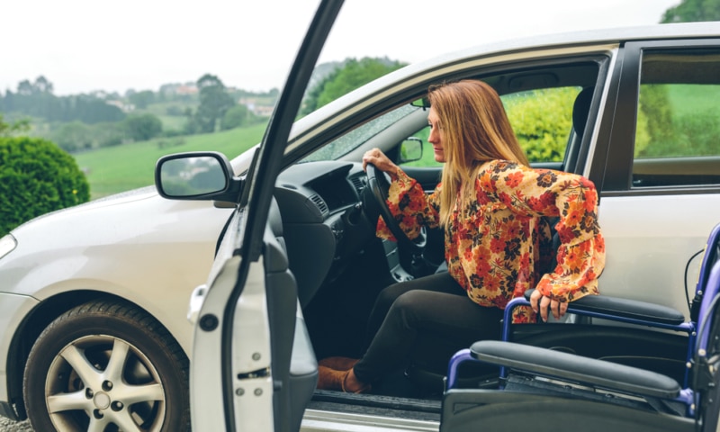 Female wheelchair user entering car driver seat