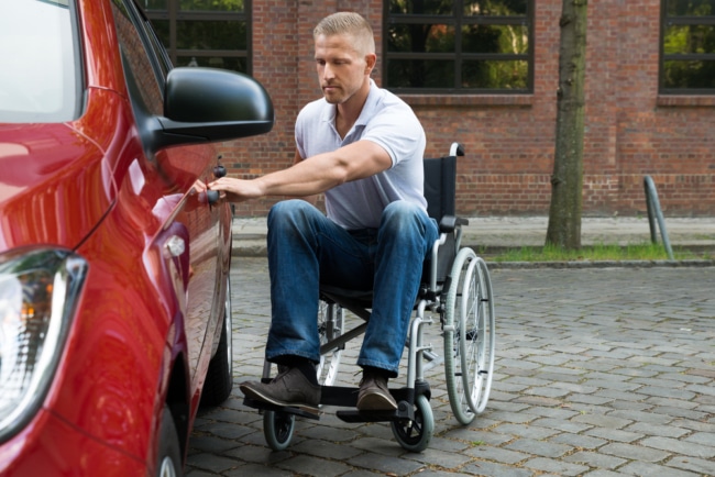 Male wheelchair user opening car door